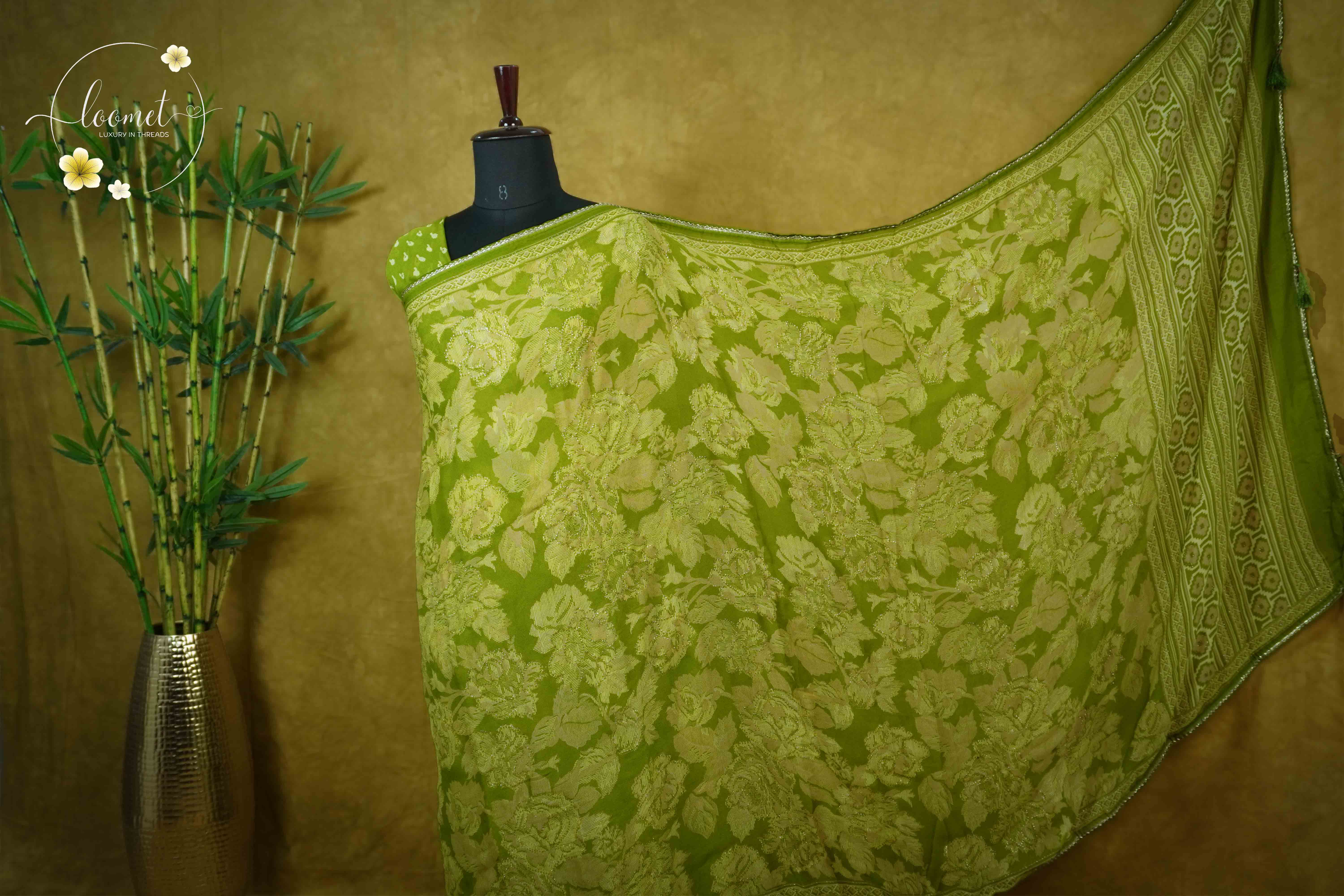 ARN1618 Olive green saree features detailed beige floral jacquard weaving, a patterned silver border, and matching tassels for an elegant finish.