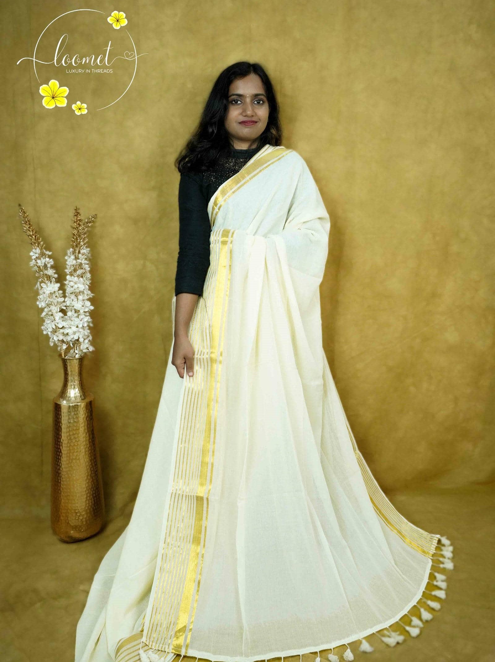 ASB25636 White saree with a minimalist design featuring a broad vertical panel with gold zari stripes by matching tassels.