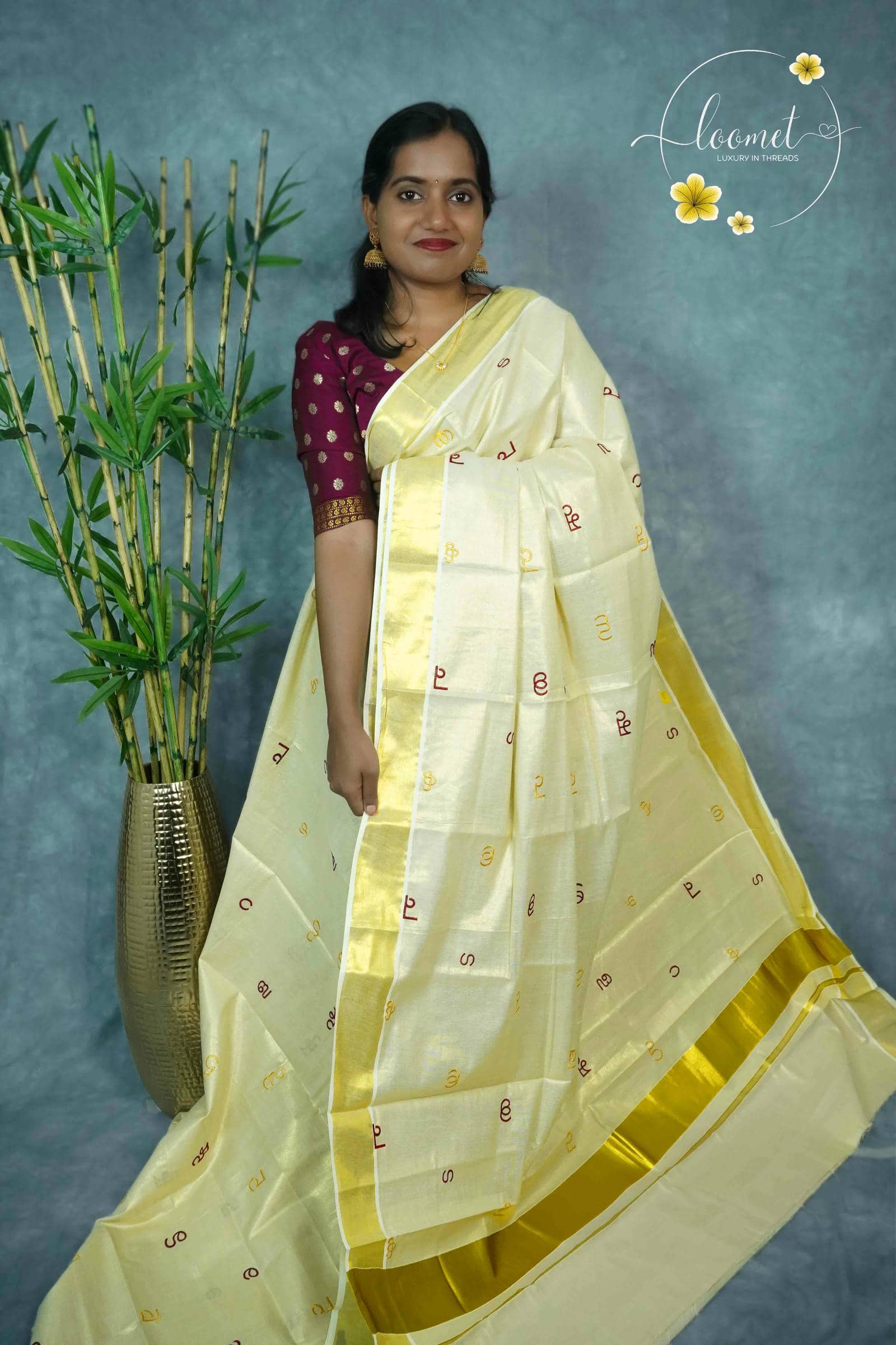 MKF3261 Cream saree features a golden border and unique multi-colored Malayalam alphabet embroidery scattered across the body.