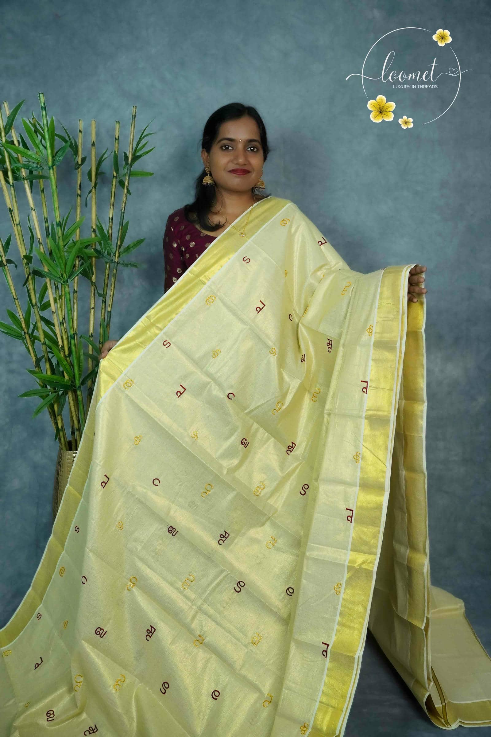 MKF3261 Cream saree features a golden border and unique multi-colored Malayalam alphabet embroidery scattered across the body.