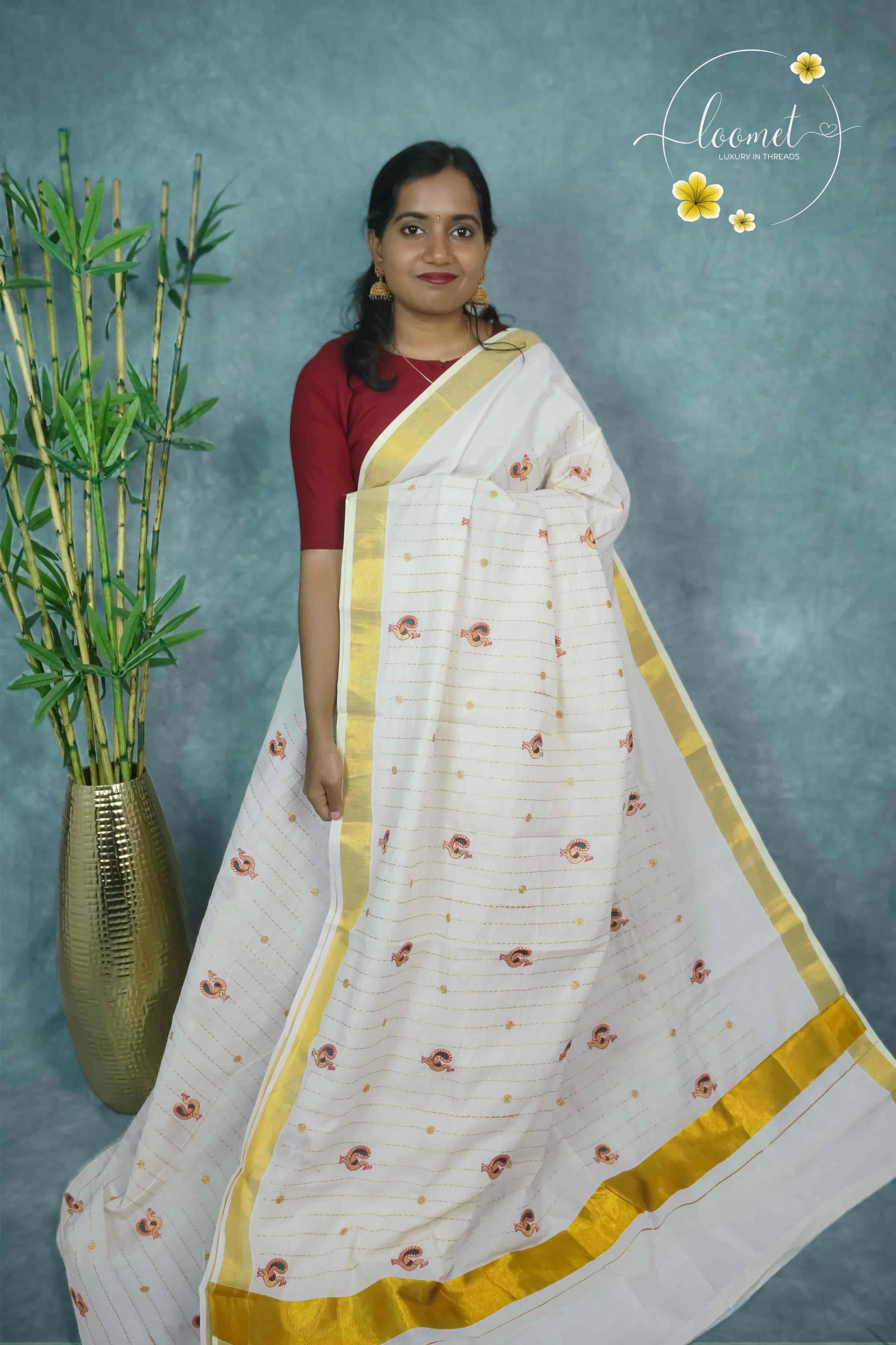 MKF3270 White saree features a golden zari border and horizontal lines adorned with small peacock and floral embroidery.