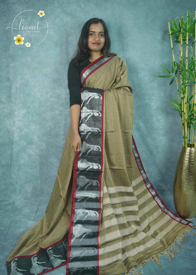 NLS1114 Beige saree features a solid body and a striking black border showcasing silver dancing figure motifs framed in red.