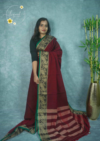 NLS1121 Maroon saree features a solid body and a wide black border detailed with intricate copper-toned peacock and floral motifs.